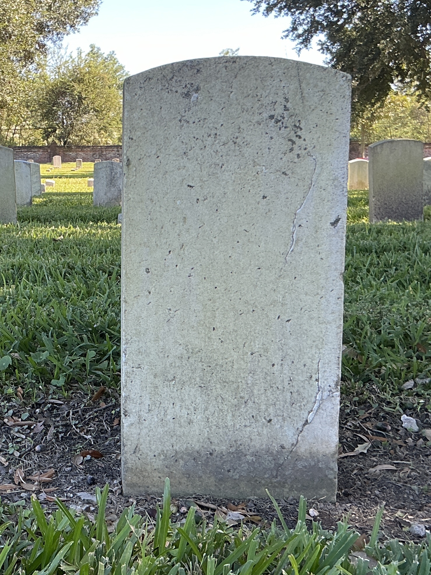 Back of historic upright marble headstone with recessed shield face.