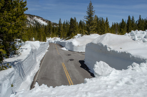 View of a paved road flanked by walls of snow