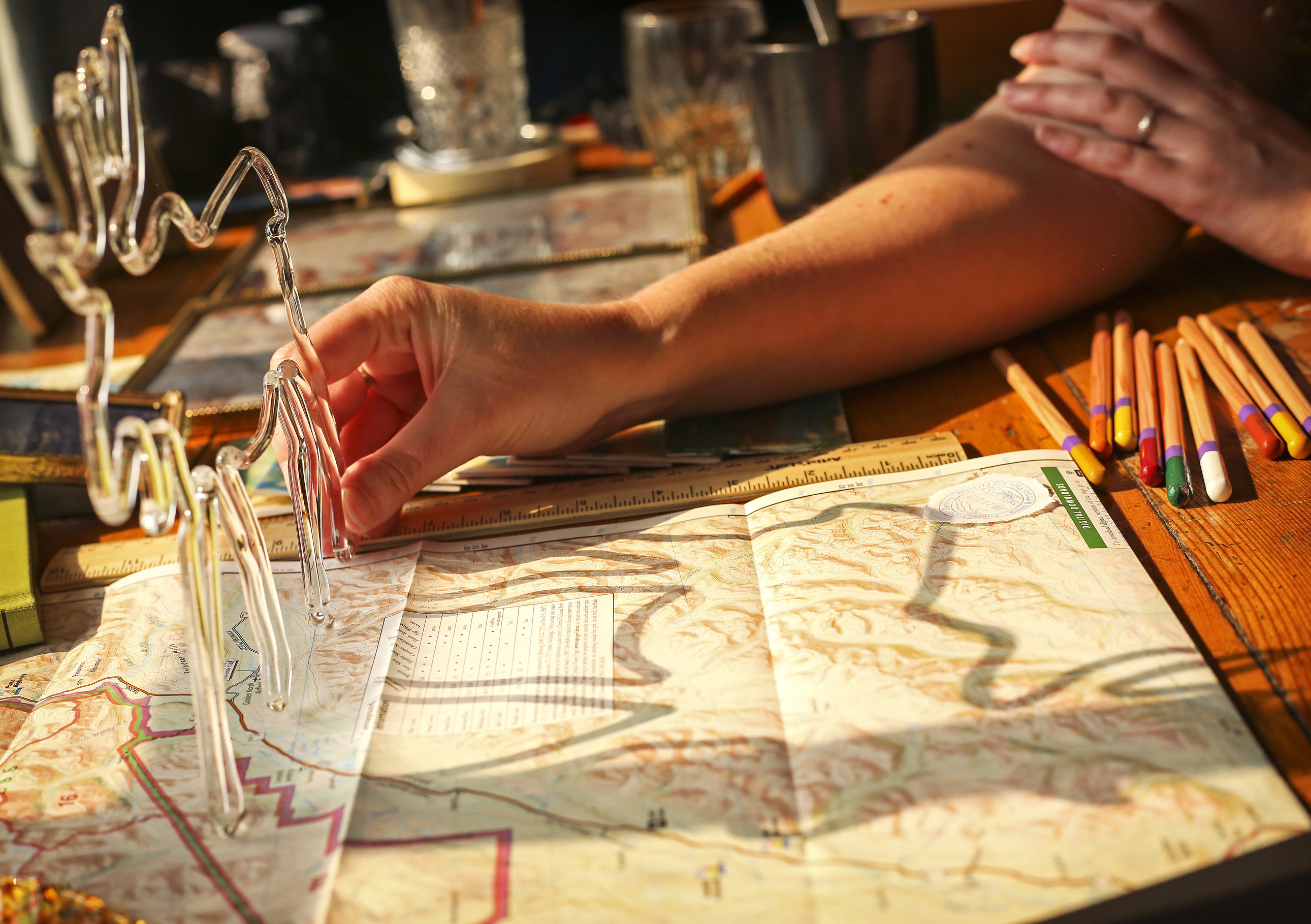 a woman holding a glass moose over a map so that its shadow casts a moose outline onto the map
