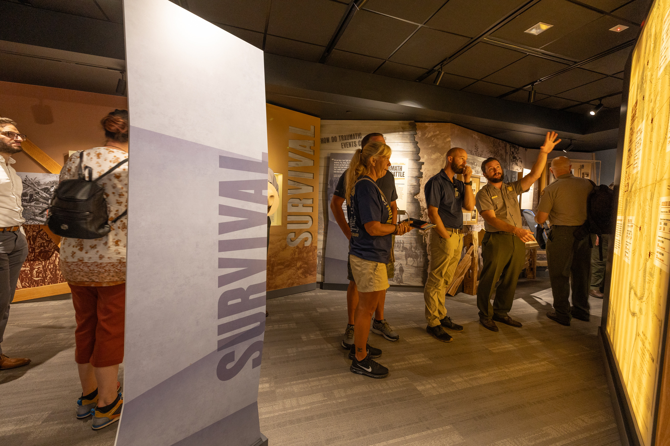 Visitors look at new exhibits in a room with a park ranger