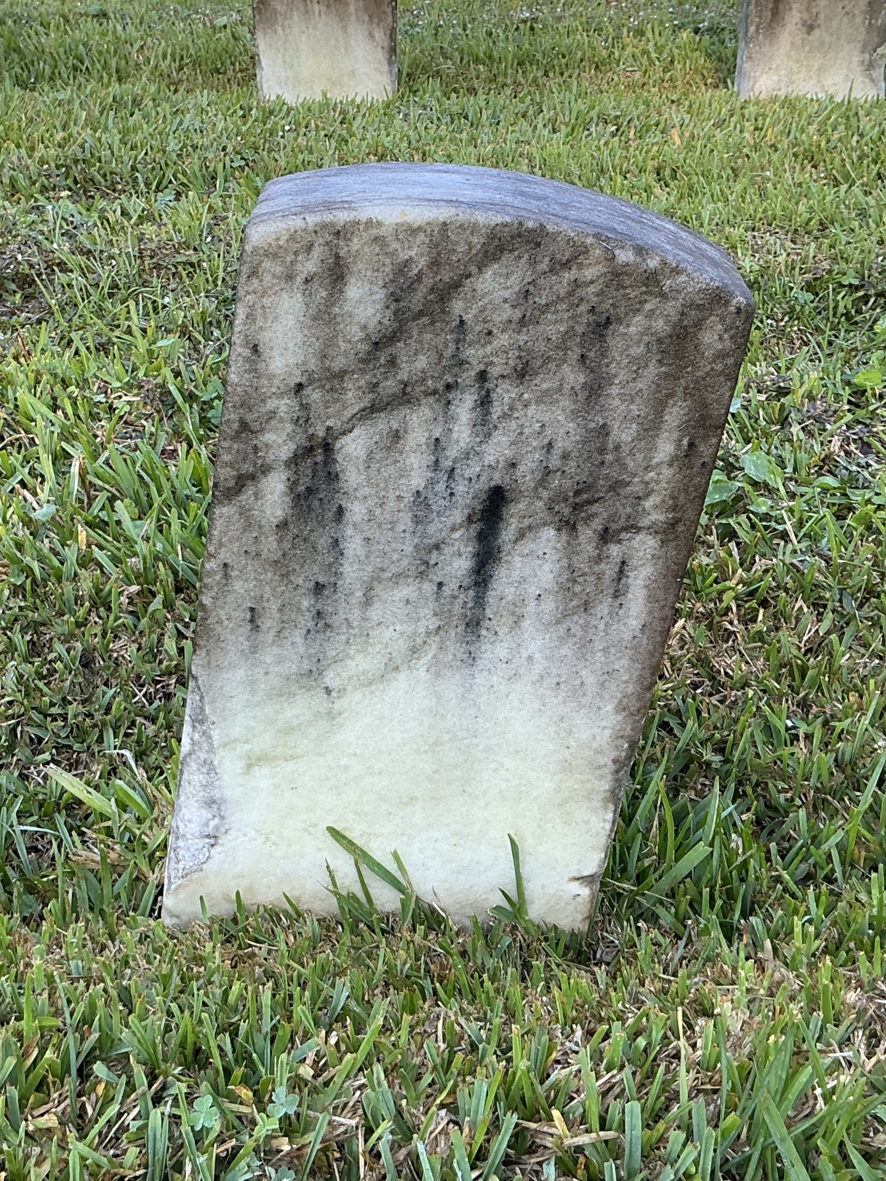 Back of historic upright marble headstone with recessed shield with recessed lettering face.