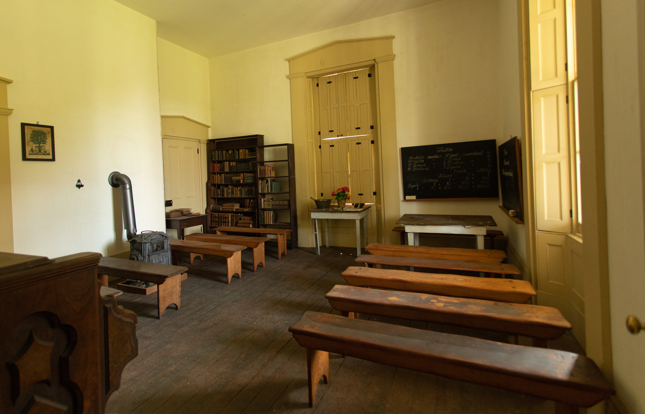 An old school room in a historic building. There are wooden benches and 