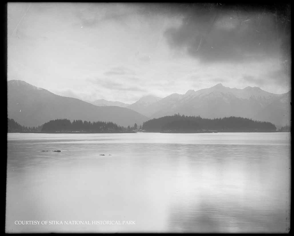 Rocky shoreline with ocean and distant mountains.
