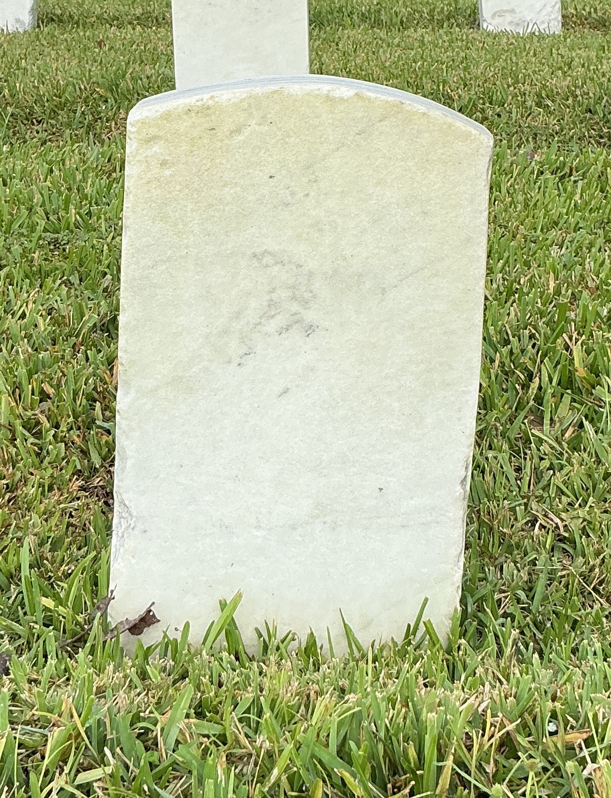 Back of historic upright marble headstone with recessed shield face.