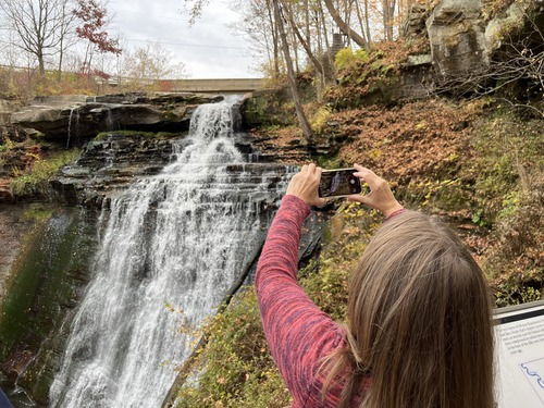 Visitor taking a picture of a waterfall 