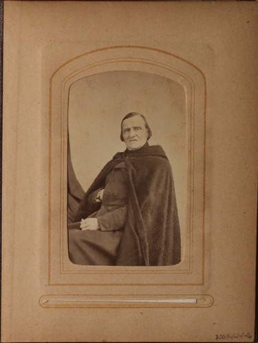 Black and white photograph of man seated in fur cape.