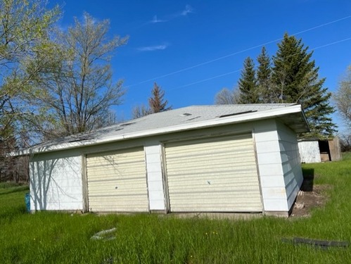Building in grass area with trees behind it.