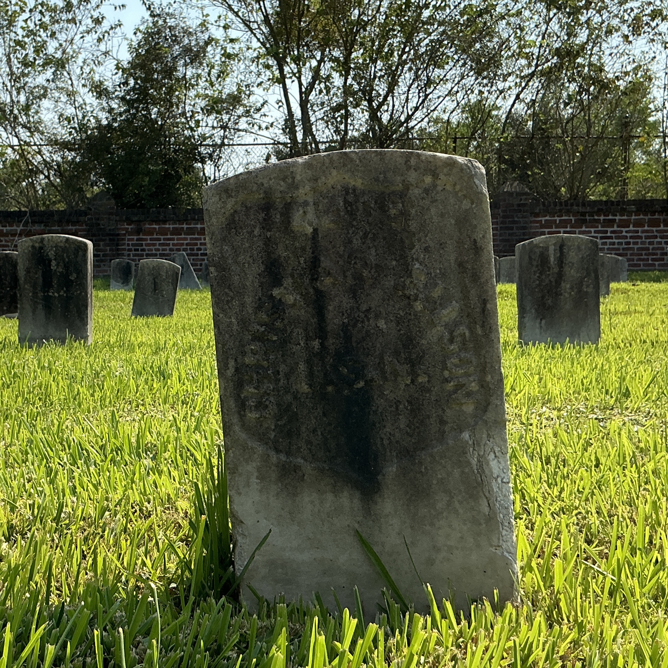 Front of historic upright marble headstone with recessed shield face.