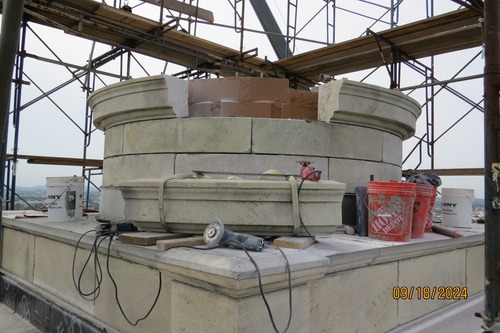 An incomplete short marble column (4 levels) with the top level having a decorative molding design. 