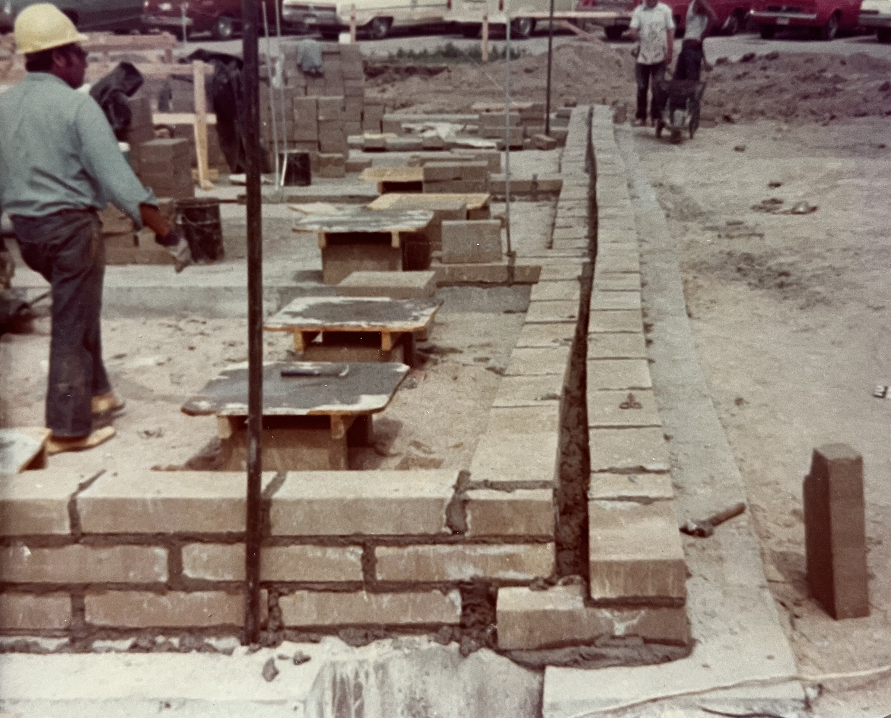 Construction workers lay two side-by-side walls of portland cement block to form the inner and center walls of the fort. 