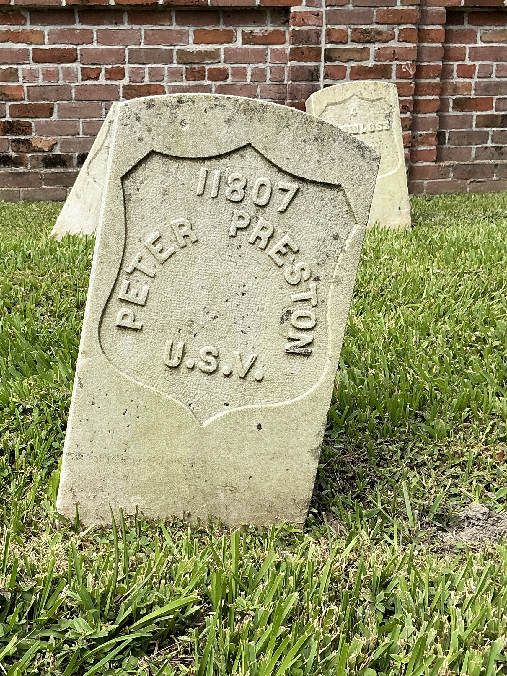 Front of historic upright marble headstone with recessed shield face.