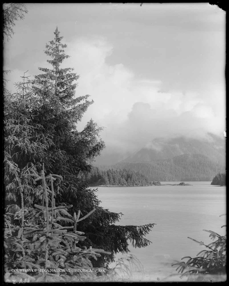 Rocky shoreline with ocean and distant mountains.