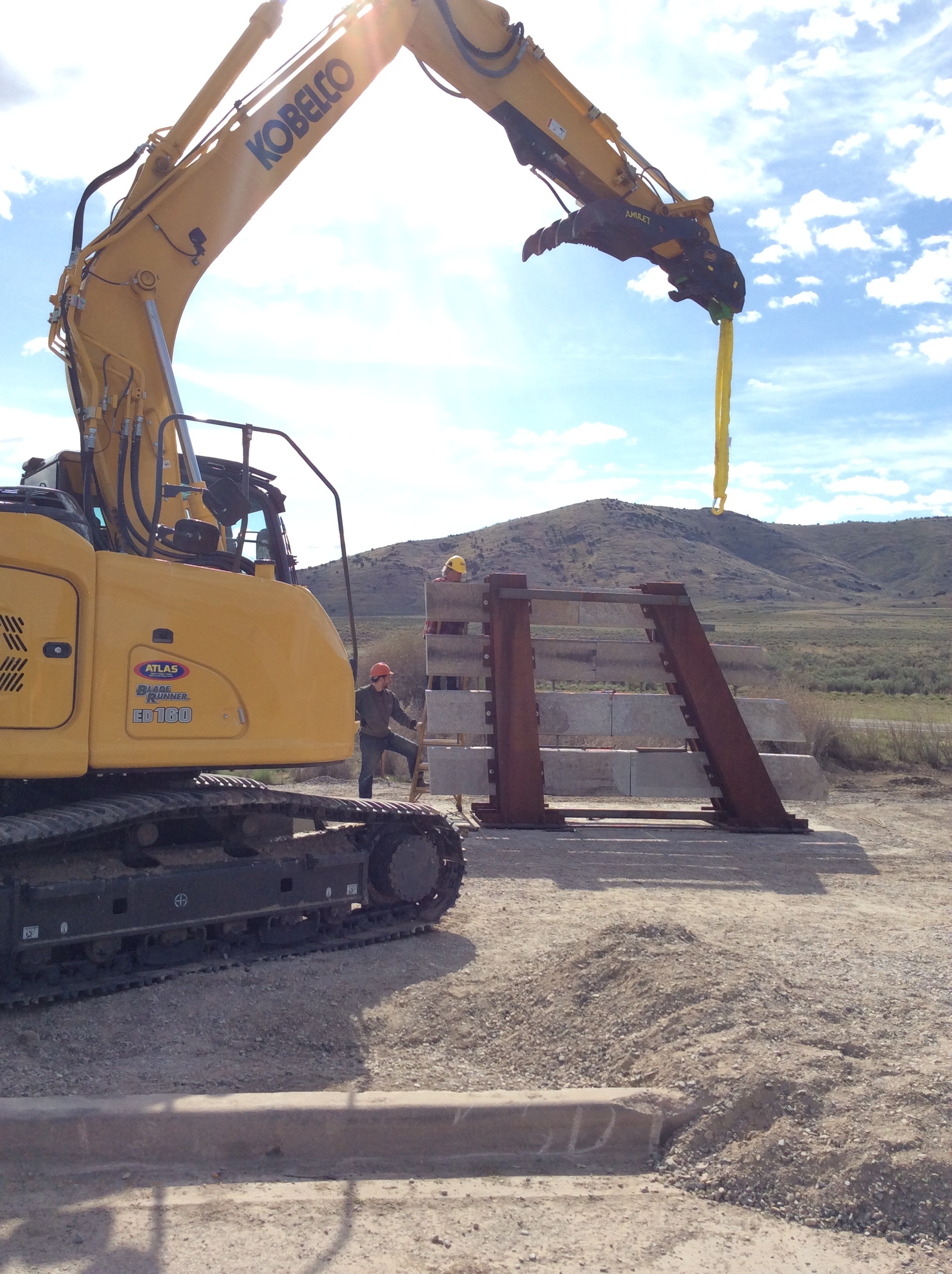 An excavator hoists the base into position. 