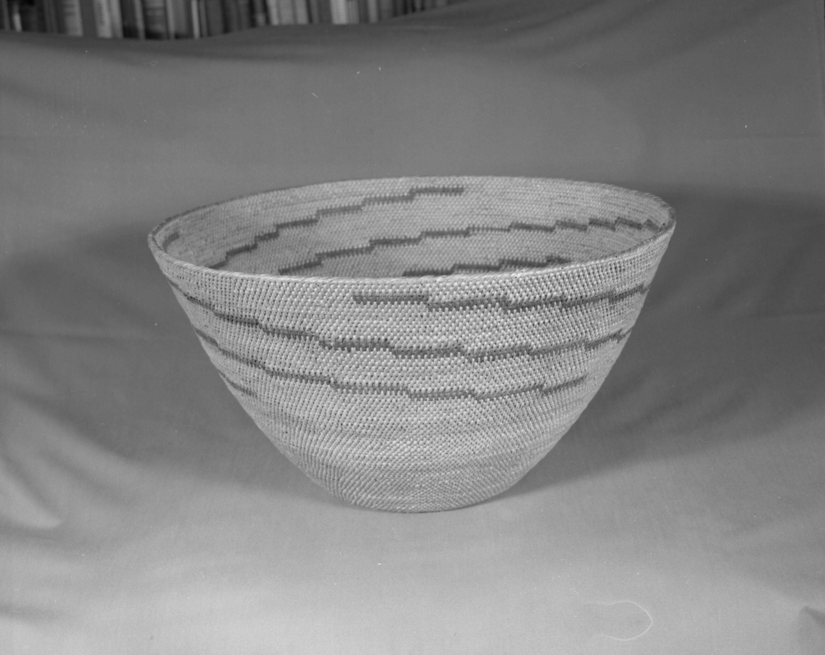 Private Collection. Object: Miwok basket. Dimensions: 17-3/4 x 10". Materials: Bull pine and bracken fern root. Technology: Single rod, fag ends trimmed on work face, moving ends trimmed on interior. Leftward coil direction, rim overstitched. Clockspring start is very fine and overstitching is over the entire top coil. Collection History: Made by Matilda, a Sonora Miwok, c. 1920. Photographed by Michael Dixon. Catalogued by Craig Bates and Barbara Beroza. Yosemite Collections, National Park Service.