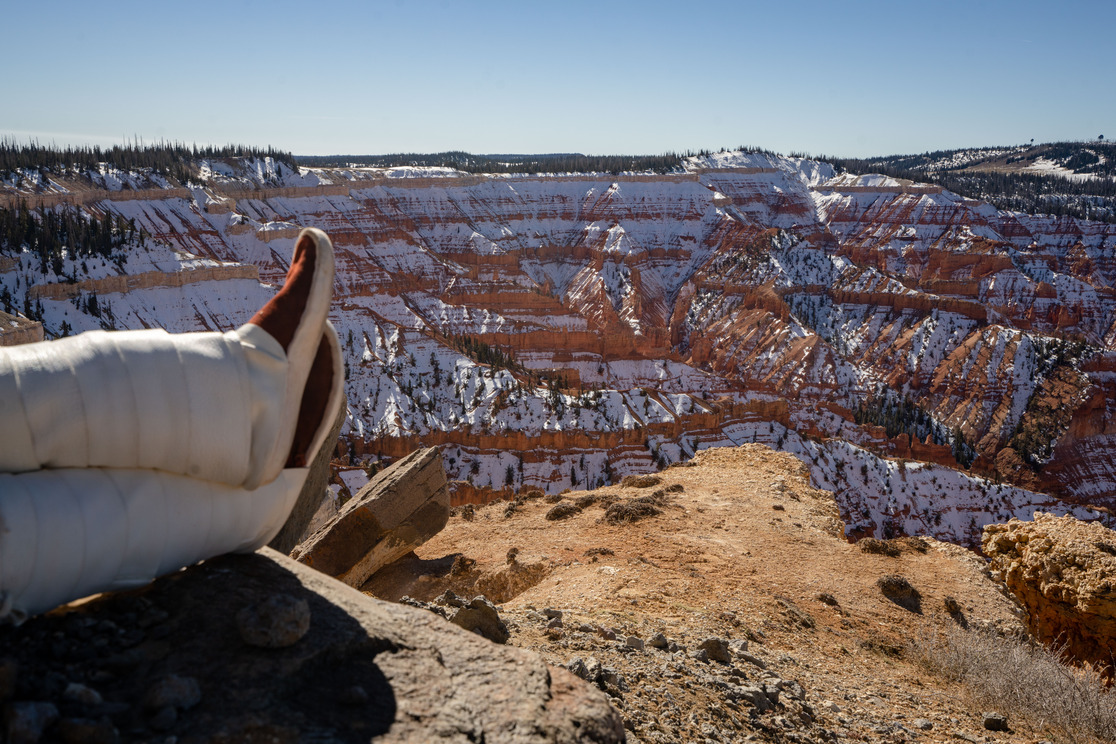 Feet wearing traditional native footwear overlooking a desert canyon dusted in snow