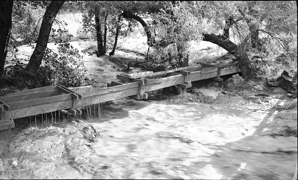 Flood damage to flume of the irrigation ditch at the Oak Creek bridge. Flume was completely removed in a later flood. Flood in progress.