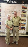 Uniformed woman and man in front of a large wall map.