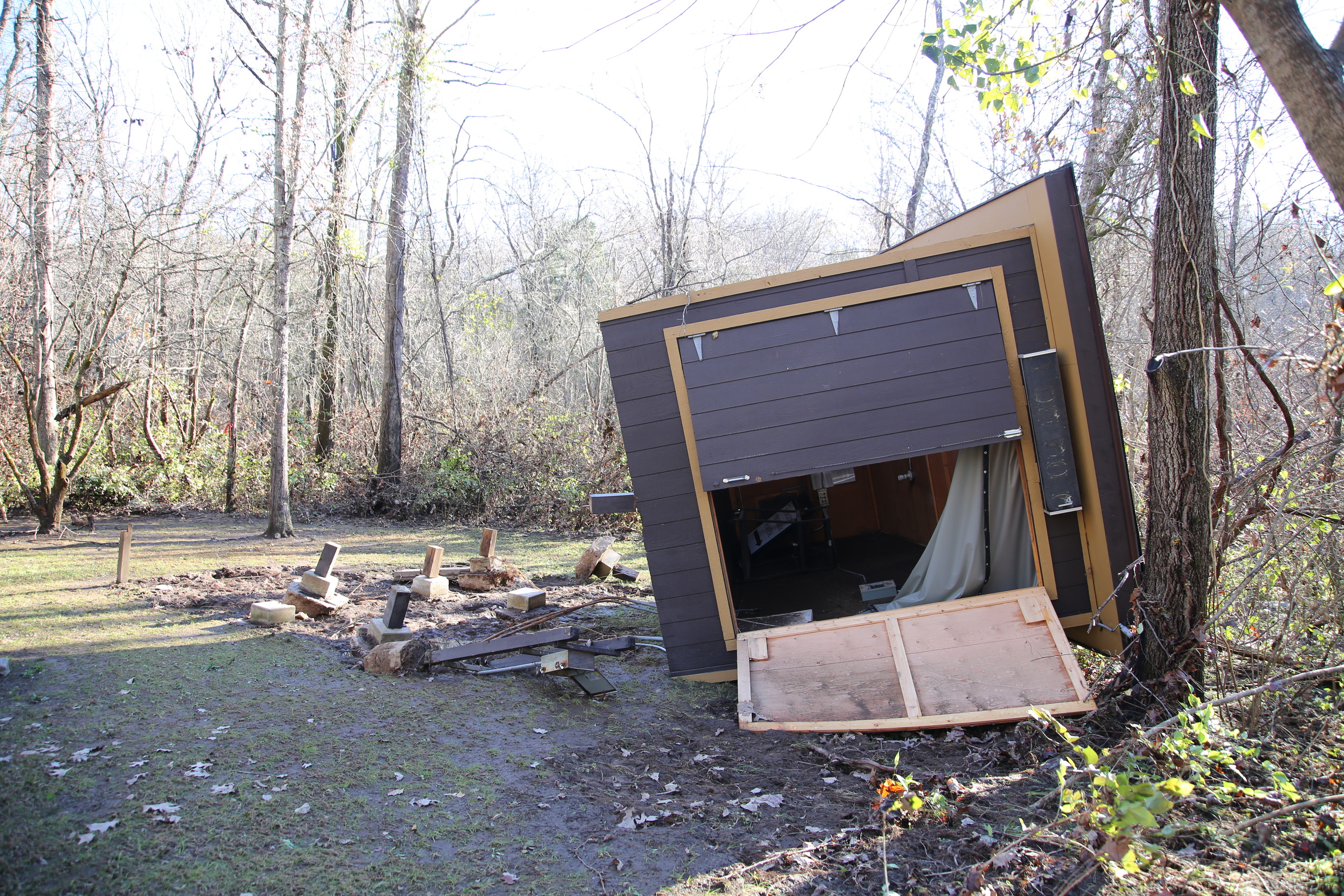A wooden shack is tipped on its side and soaked.