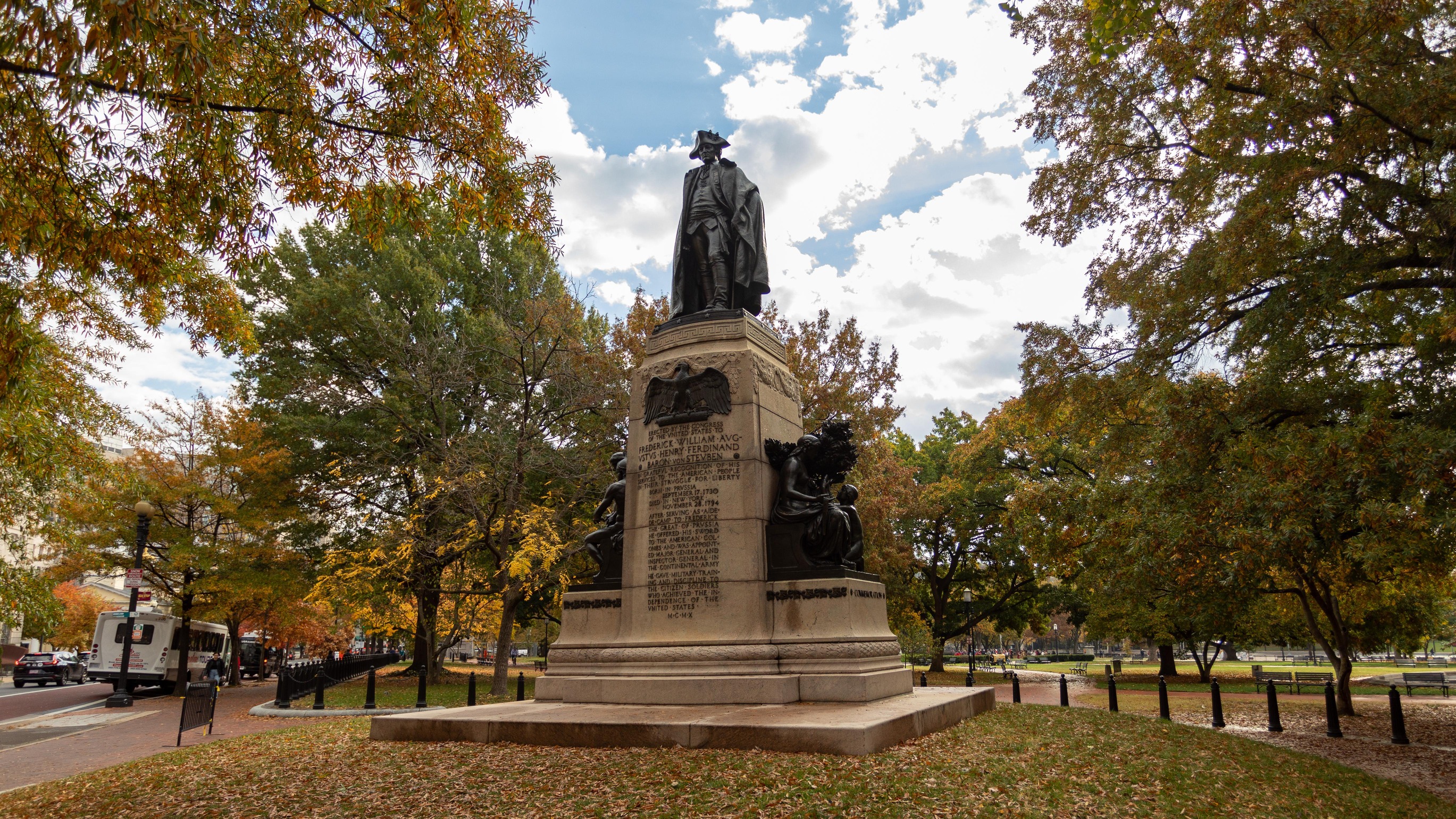 A statue of General Von Steuben on top of a tall pedestal with an inscription of his service to the country.