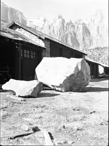 Rock fall - damage to storage shed (currently the Roads and Trails Shop) view from above of hole in roof, low boy trailer damaged and another vehicle with rock on top. Handwritten note on card: In one great rock fall one segment went through the roof and destroyed a new car. A larger mass rolled over the low boy trailer and mashed another vehicle into the ground.