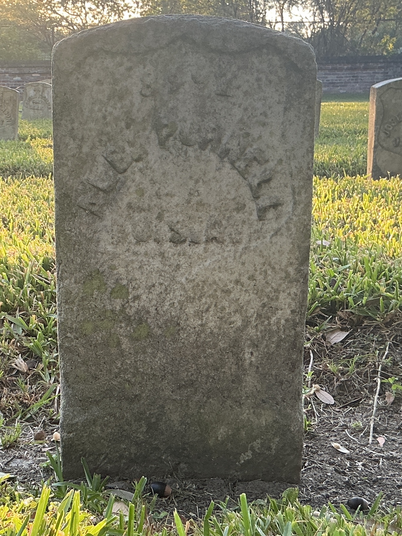 Front of historic upright marble headstone with recessed shield with recessed lettering face.