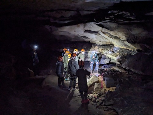 Ranger talks to group of children inside cave. 