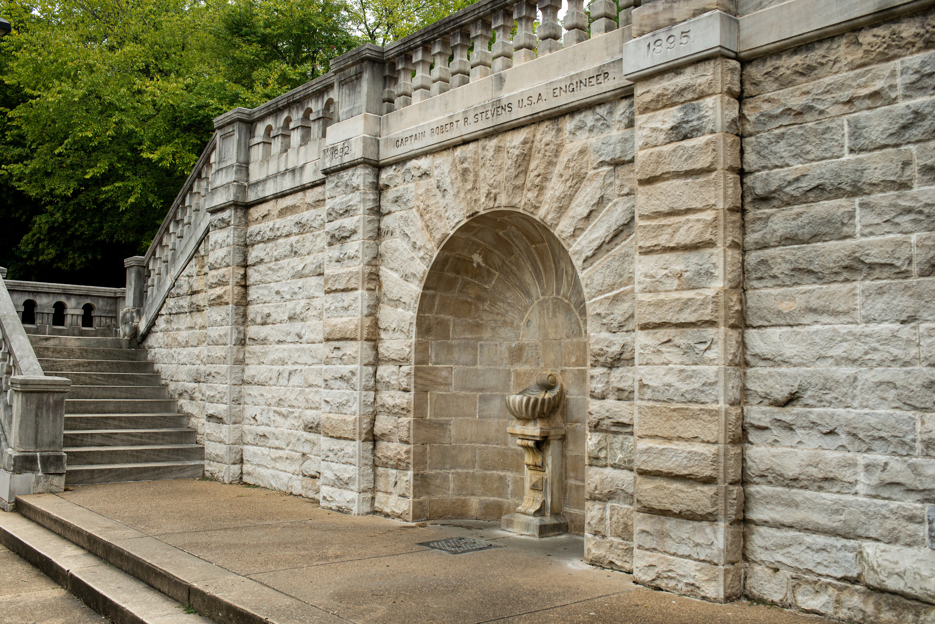 Large and elaborate stone staircase with an outcropping in the center with a fountain shaped like a shell atop a pedestal at the center.