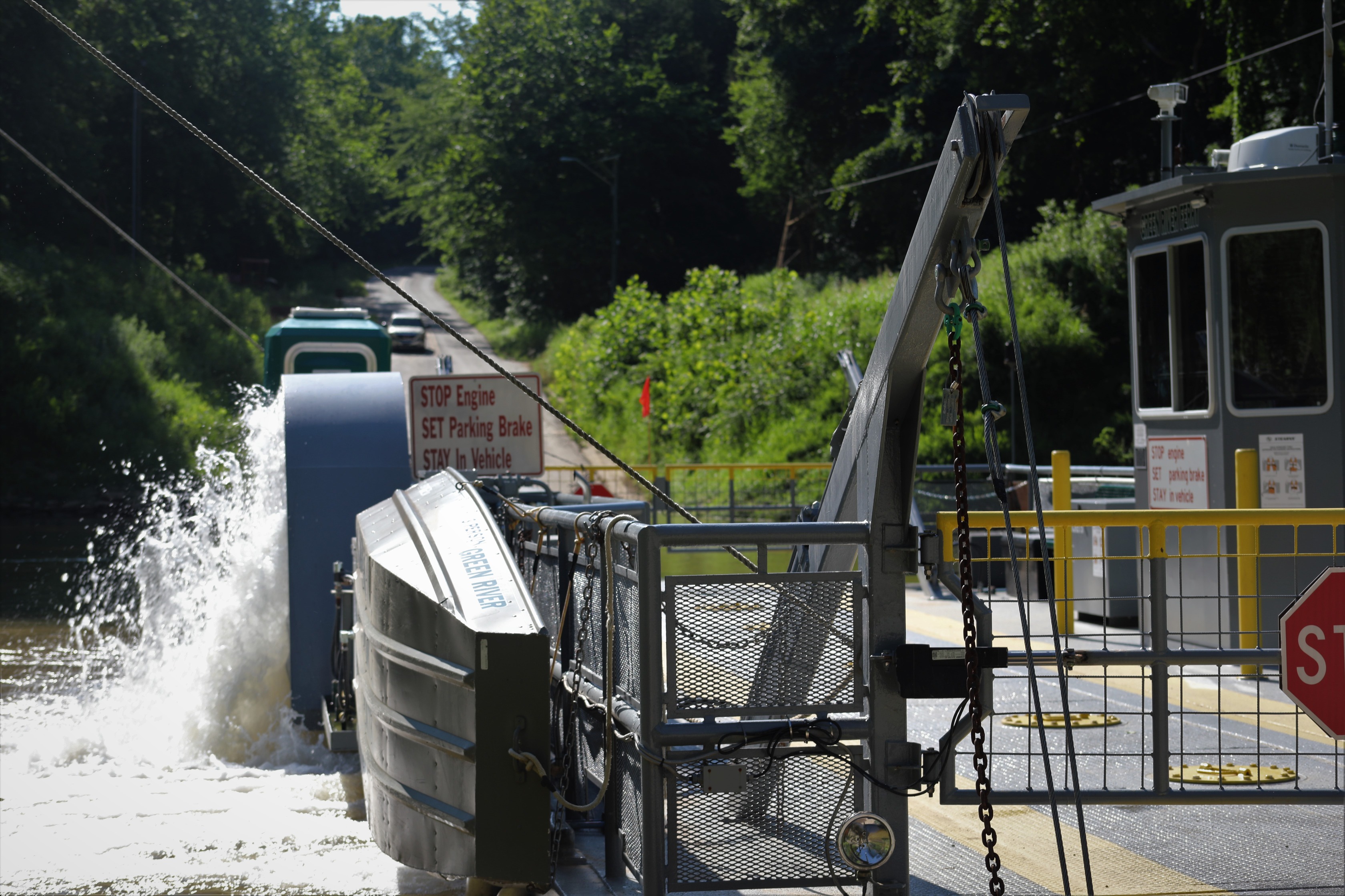 The ferry boat splashes water as it moves across the river. 