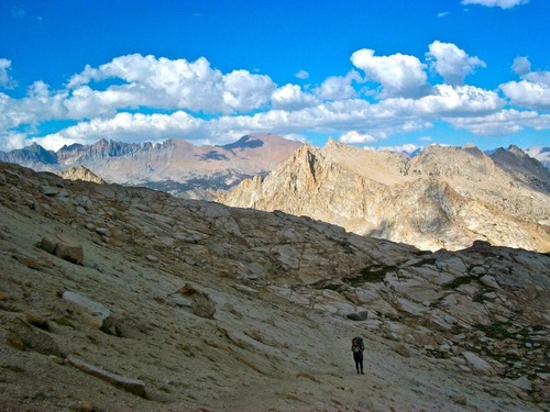 A bright blue sky with puffy clouds and granite peaks