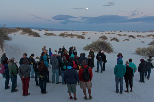 A large group of visitors join a ranger for a guided full moon hike.