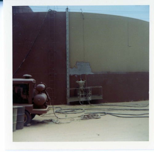 Man repainting the exterior of the million gallon water tank at Birch Creek.