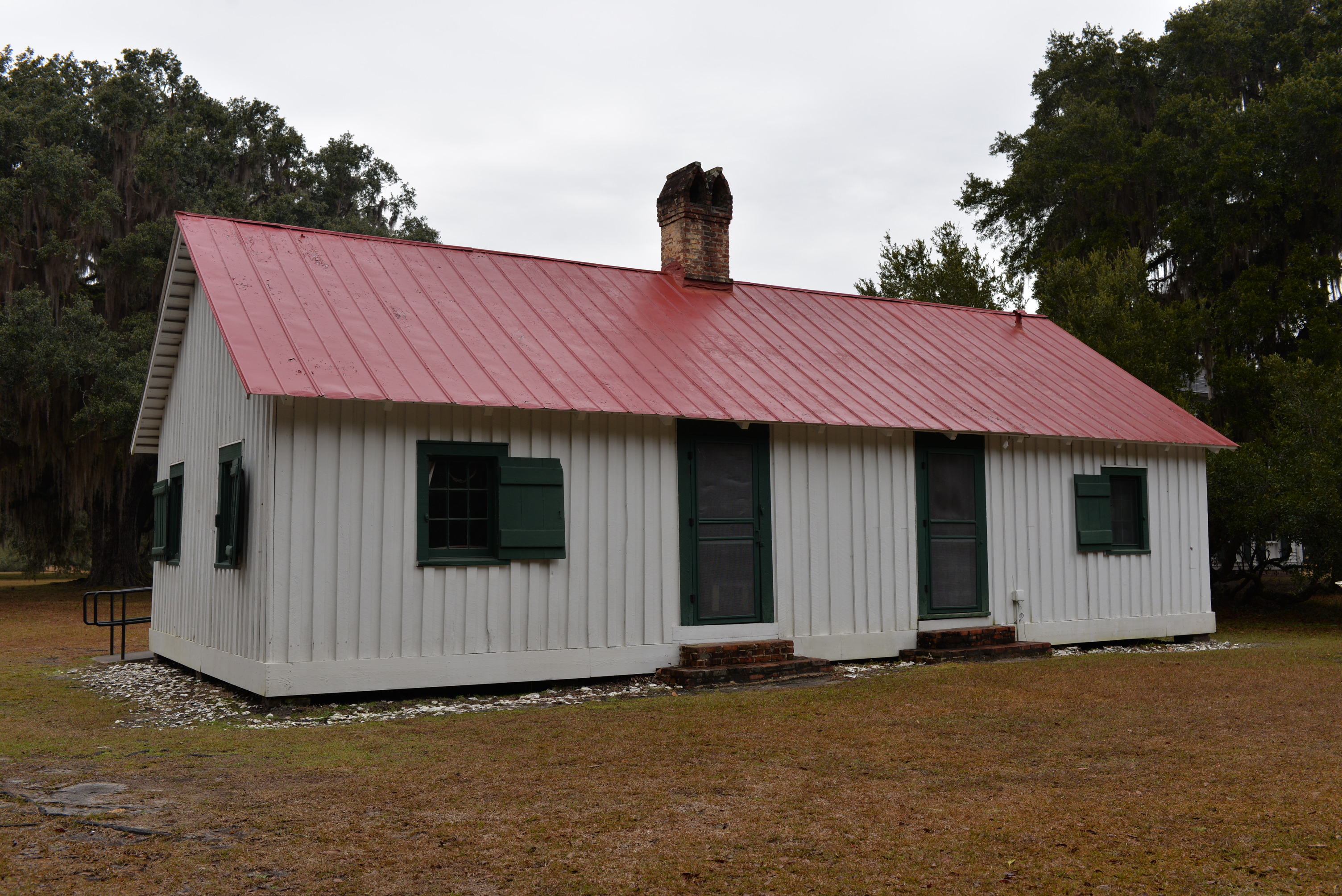 White sided structure with metal roof and centralized chimney.