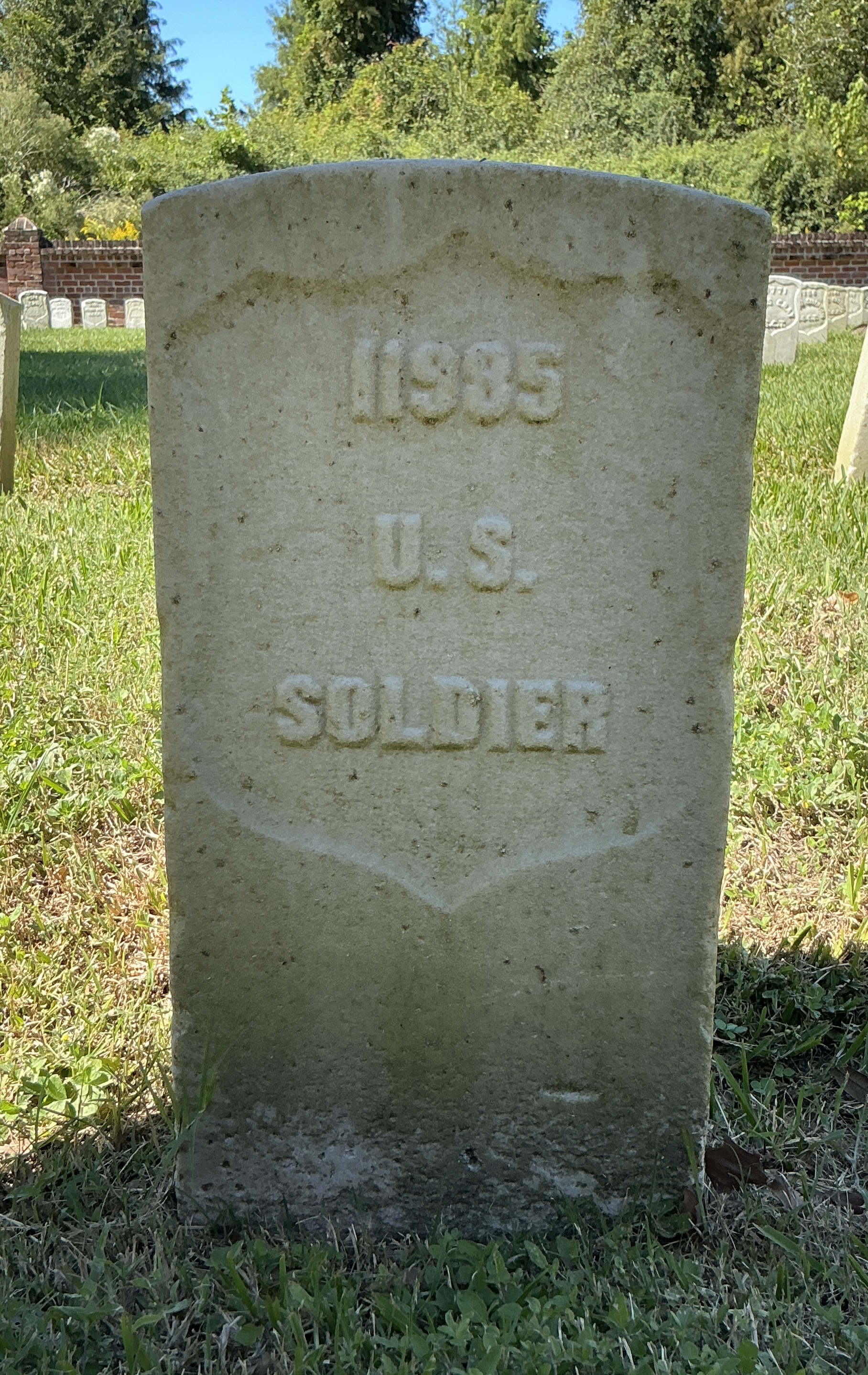 Front of historic upright marble headstone with recessed shield face.