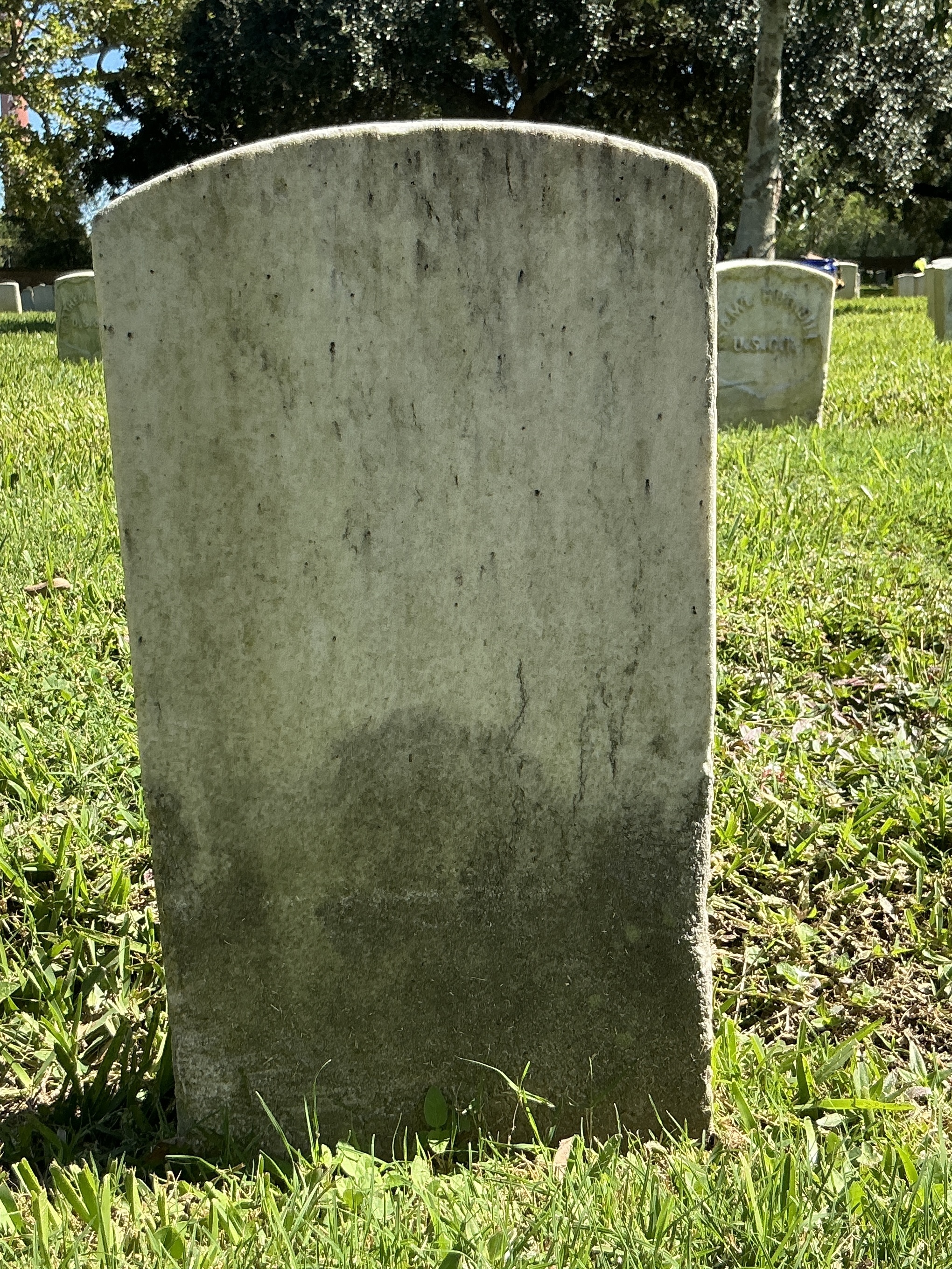 Back of historic upright marble headstone with recessed shield face.