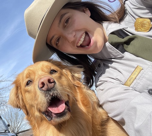 A selfie of a golden retriever and a female NPS ranger. 
