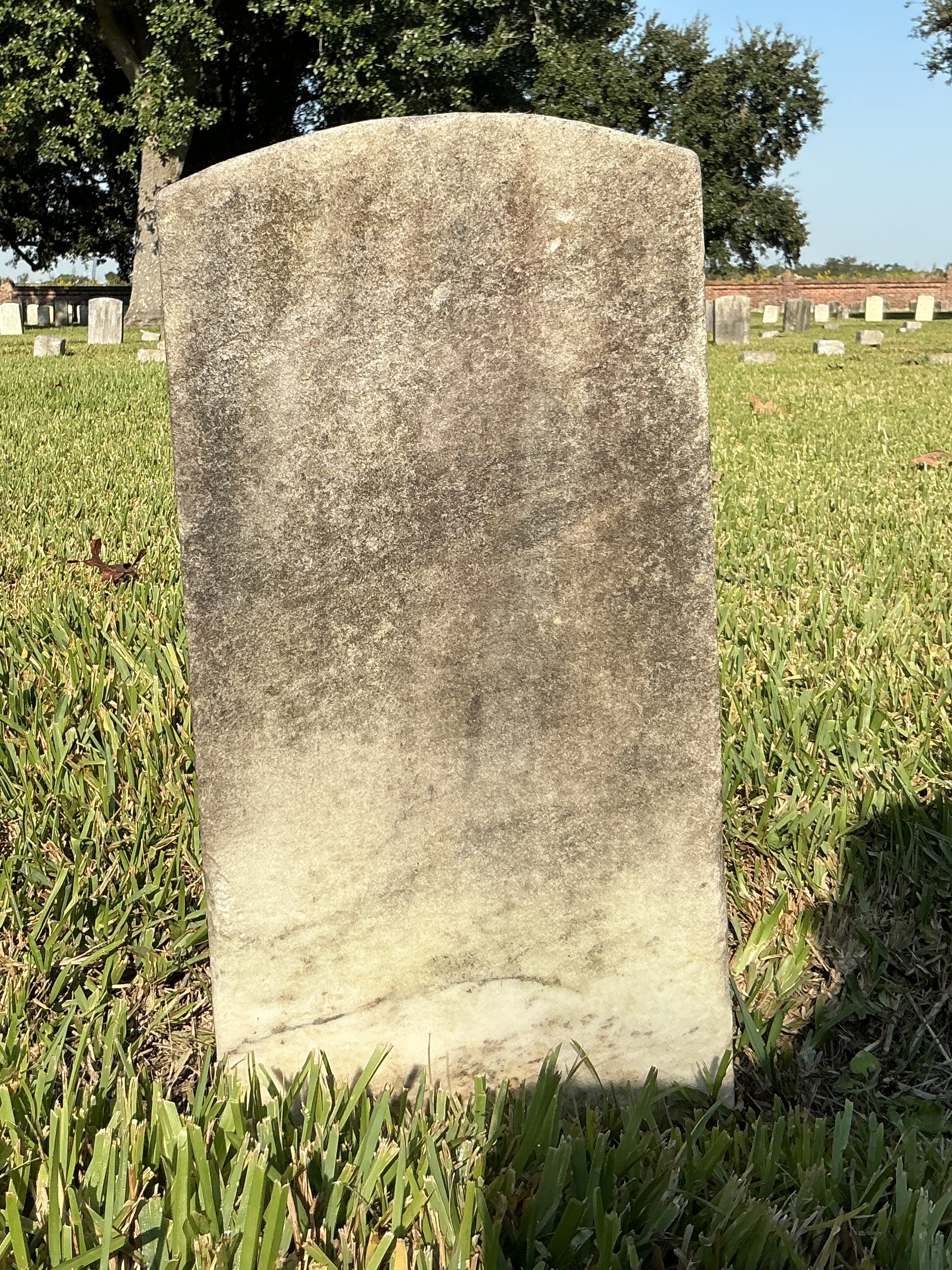 Back of historic upright marble headstone with recessed shield with recessed lettering face.