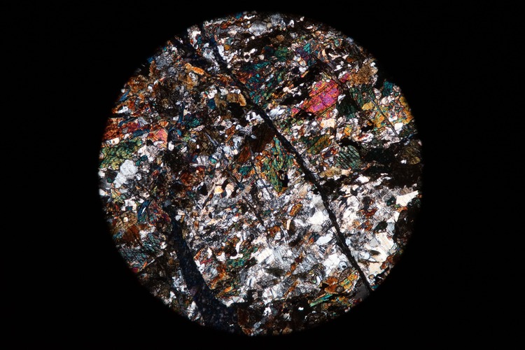 Circular microscopic image of rock structure.