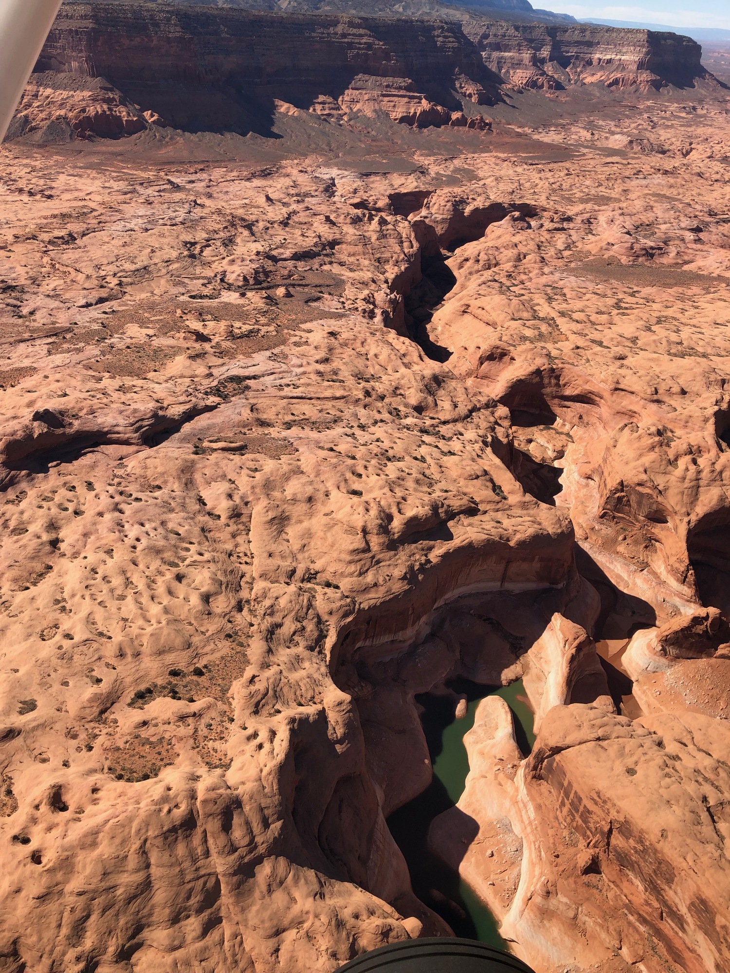 Large sandstone cliffs over smaller canyon and shallow water.