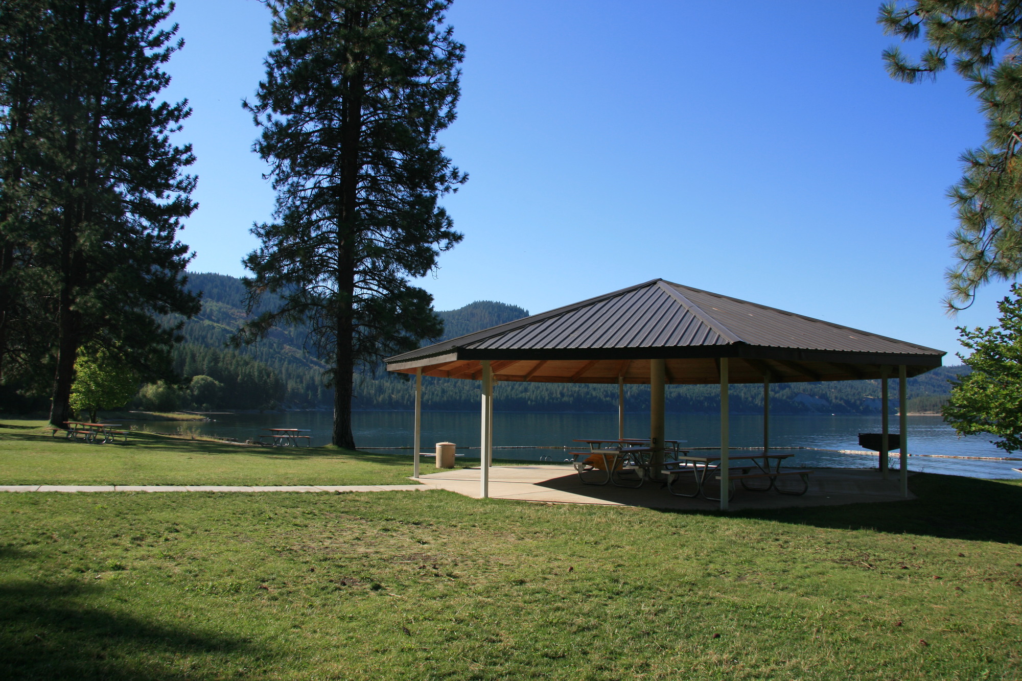 Color photograph of a covered picnic shelter on the banks of a lake