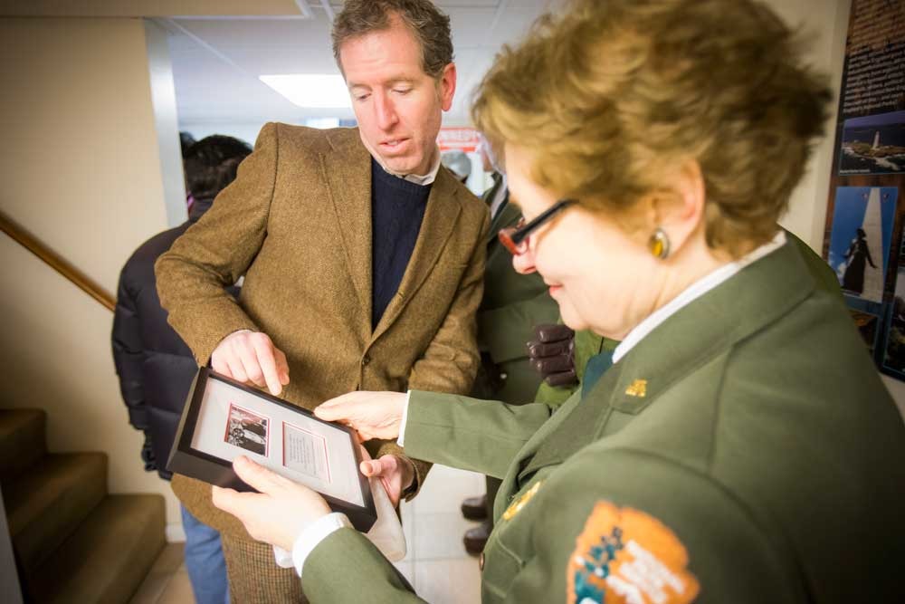 A man hands a woman a framed image