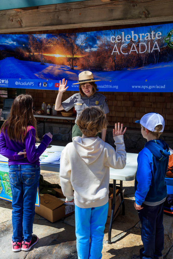 Three children being pledged in as junior rangers by a park ranger.