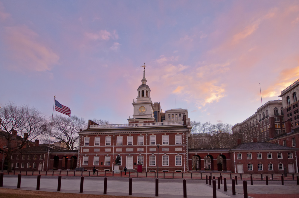 Color image showing a row of brick 18th-century buildings during sunset, with more modern office buildings in the background.