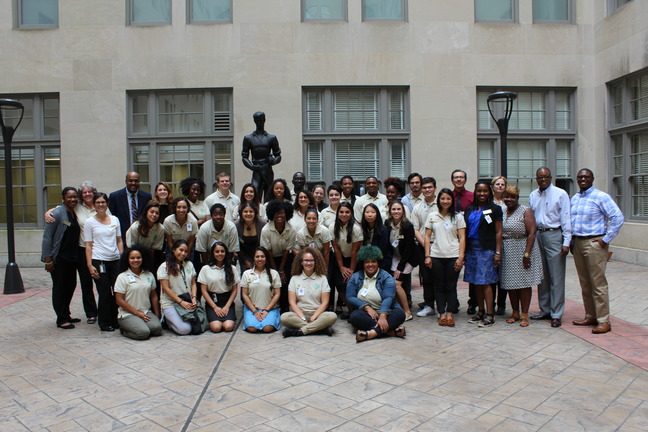 A group of students and program coordinators pose for a group photo in a stone courtyard.