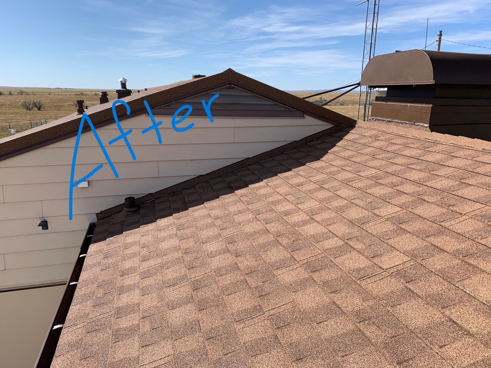 A roof of a building with beige walls and reddish brown colored shingles.