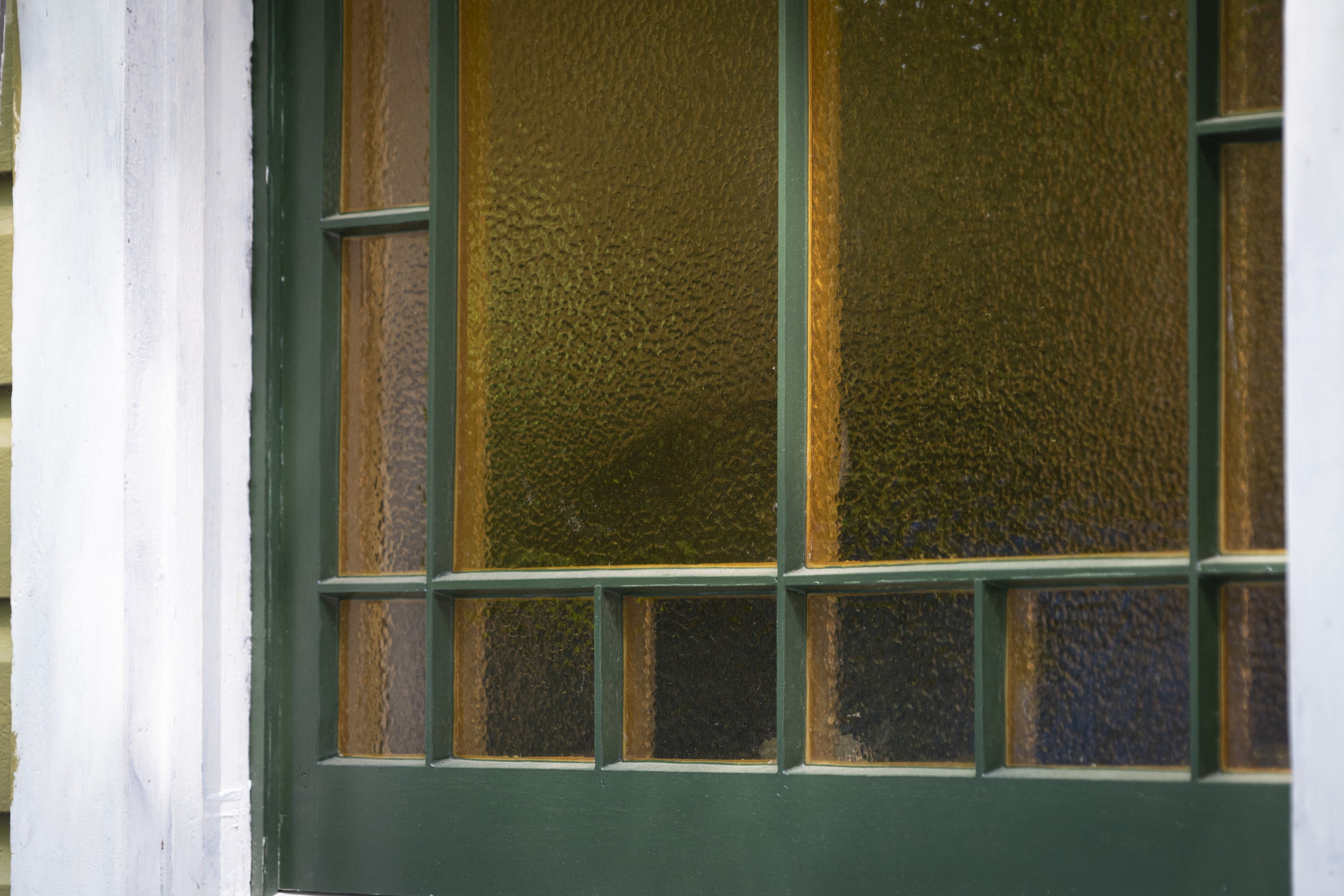 A textured yellow glass window in a dark green frame.