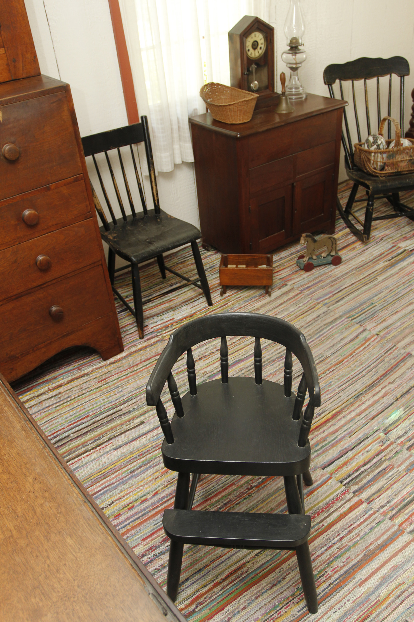A facsimile of an antique high chair is part of the furnishings in the living area of an 1800s cottage.
