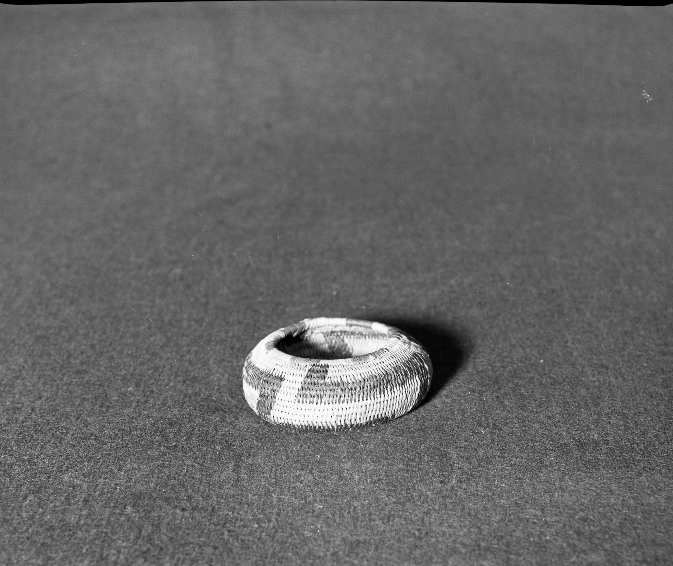 Marie Rozier Collection, Catalog No. 152. Object: Pomo basket. Dimensions: 3 1/2" diameter x 1 1/4" height. Materials: sedge root, willow rod, redbud, bullrush. Technology: interlocking stitch, bullrush used on top coil only, remnants of quail topknots and cotton thread (which probably was a clam bead handle). Collection History: Gift from M. Long. Photographed by Michael Dixon, December 1982. Catalogued by Craig Bates and Barbara Beroza. Yosemite Collections, National Park Service.