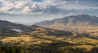 Looking across rugged country at a hot spring terrace in the distance and a mountain in the background.