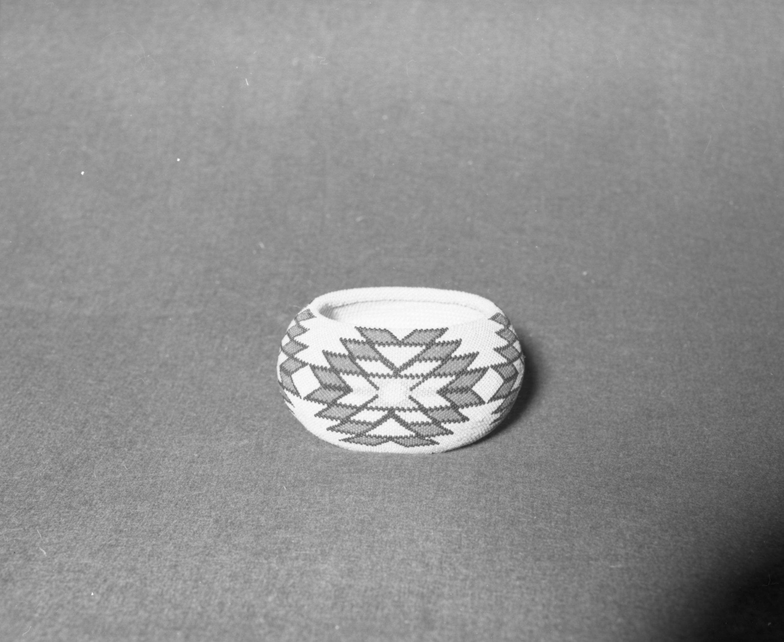 Mrs. Donald Segerstrom Collection. Object: Paiute beaded basket. Dimensions: 5 x 2 1/2". Materials: split willow, glass beads. Technology: single rod, non-interlocking stitch, beaded single bead brick stitch with a turquoise blue background. Collection History: purchased from Carrie Bethel by Donald Segerstrom ca. 1960. Photographed by Michael Dixon, January 1983. Catalogued by Craig Bates and Barbara Beroza. Yosemite Collections, National Park Service.