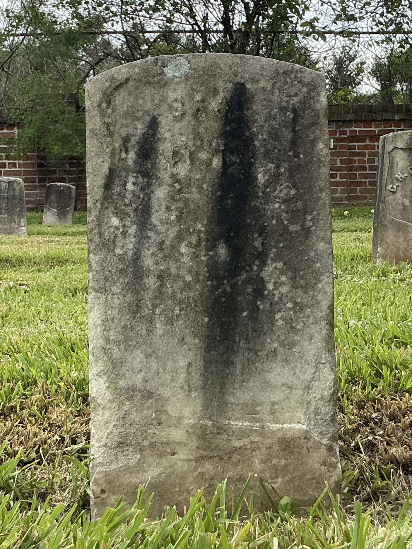 Front of historic upright marble headstone with recessed shield face.